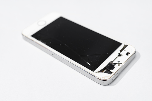 Smartphone with broken screen isolated on gray background. Damaged mobile phone