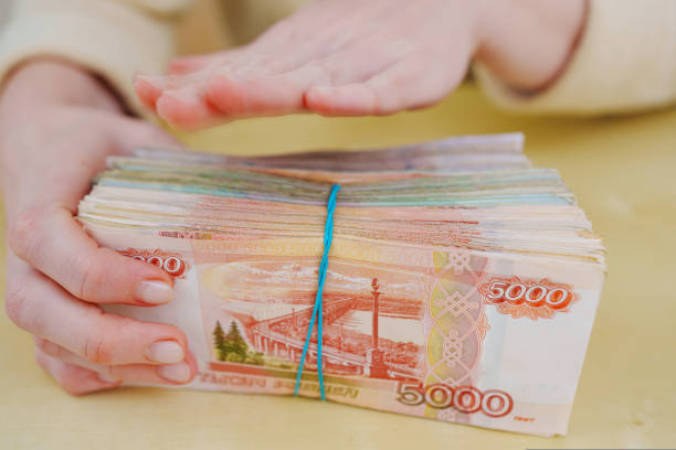istock women's hands hold a stack of rubles tied with a rubber band. 1441450493
