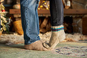man and woman legs in woolen socks against background of fireplace