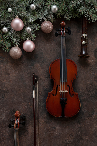 Old violin and flute with fir-tree branches with Christmas decor. Christmas and New Year's concept. Top view, close-up on dark concrete background