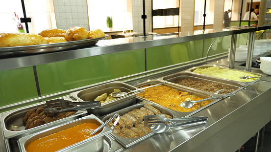 close-up, showcase of Self service restaurant with a variety of dishes, buckwheat porridge, mashed potatoes, vegetable stew with gravy, sausages, mini pizza, pies, sauces. High quality photo