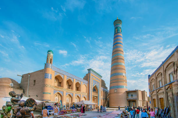 Minaret Islam-Khoja 05-11-2022  Khiva Uzbekistan. Idyllic view on  Islam-Khoja minaret and cafe waiters and just walking Uzbeks  in Khiva old city khiva stock pictures, royalty-free photos & images