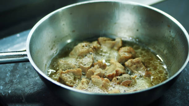 close-up, o cozinheiro prepara diferentes alimentos no fogão. chef profissional assa cebola e cenoura, ele trabalha em uma cozinha moderna com ingredientes diferentes - pan frying pan fire fried - fotografias e filmes do acervo