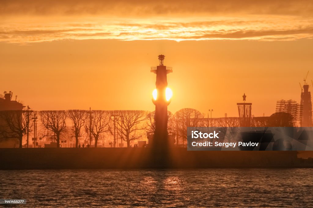 Sun setting behind the rostral column Russia, St. Petersburg, Rostral column on the banks of the Neva River in the rays of the setting sun Abstract Stock Photo