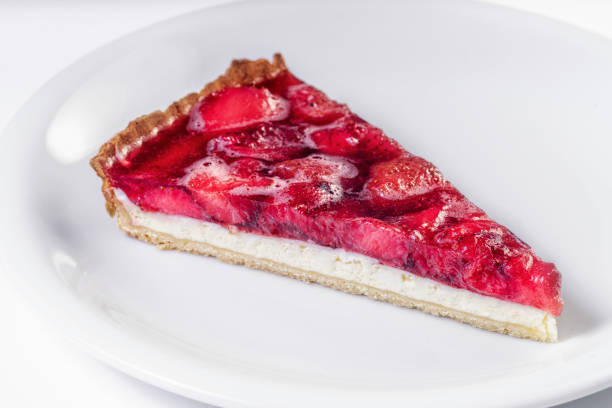 Piece of cheesecake with fresh strawberries and mint on white plate