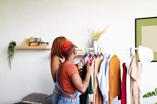 Two black women choosing clothes in second hand shop