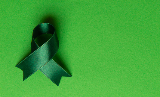 Green awareness ribbon on green background.