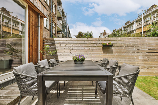 A small backyard behind a cozy house with a separate sitting area, surrounded by a wooden fence