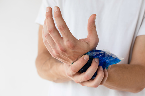 Man holding ice bag compress on a painful wrist.