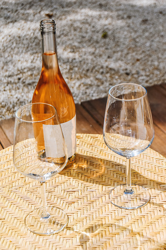 A bottle of wine and a couple of glasses standing on a small table, close-up