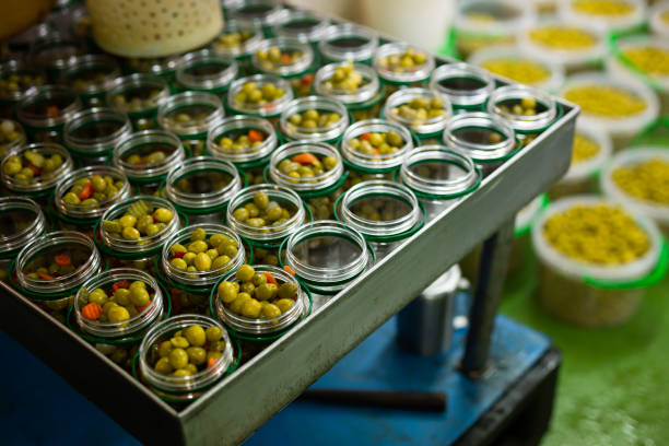 remplissage de bocaux en verre avec des olives marinées - manufacturing occupation photos et images de collection