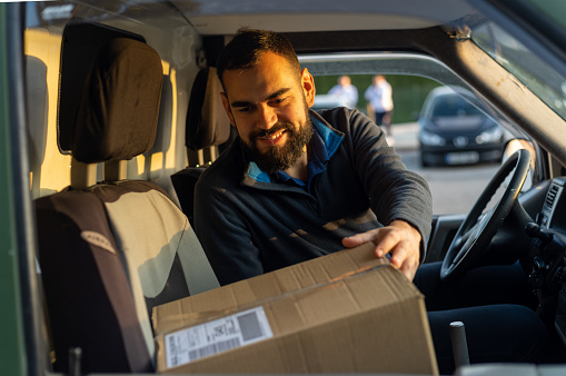 Delivery man working inside a van holding a parcel ready to deliver.