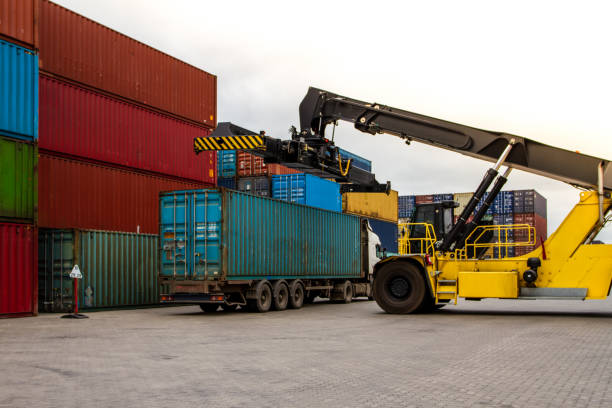 istock Truck while loading in logistic shipping yard with cargo container. Forklift truck handling truck. Logistic import export concept. Loading and unloading of containers in the port. 1441478211