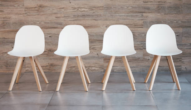 istock Hiring staff recruitment drive, interview waiting room and four white office chairs in empty wood wall background. Business opportunity in corporate space and available position to join the team 1441482505