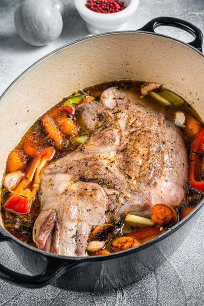 istock Braised lamb mutton shoulder in a baking dish with vegetables in red wine. White background. Top view 1441483153