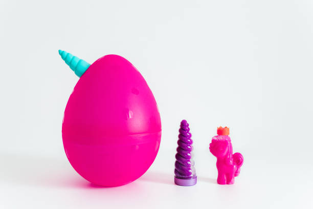 большое пластиковое розовое яйцо единорога и игрушки внутри со слизью. белый фон. популярная пластиковая игрушка с сюрпризом внутри. - kinder surprise стоковые фото и изображения