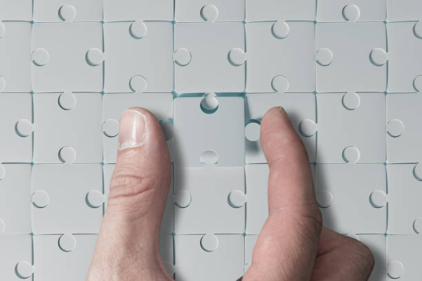 istock The hand puts a blank puzzle with no content. 1441488635