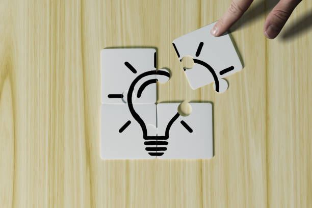 istock Hand puts a puzzle with a piece of light bulb. 1441488657