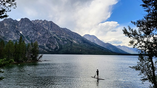 A paddle boarder ventures out onto Jenny Lake, Grand Teton National Park, Wyoming, USA