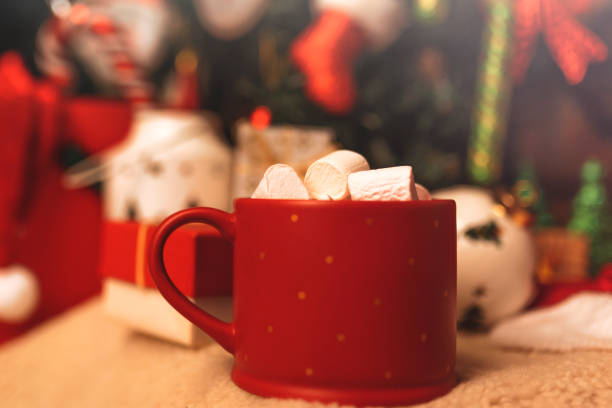 Close up view of a red mug filled with hot chocolate, candy cane and marshmallows isolated on white background. Christmas decoration complete the composition. Copy space available. High resolution 42Mp studio digital capture taken with Sony A7rII and Sony FE 90mm f2.8 macro G OSS lens
