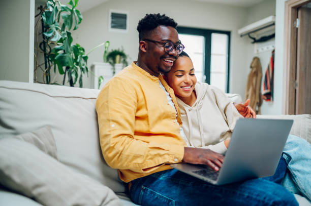 istock Multiracial couple using laptop while sitting on a sofa at home 1441495136