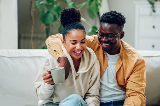 istock Multiracial couple relaxing on a couch at home and drinking coffee 1441495176