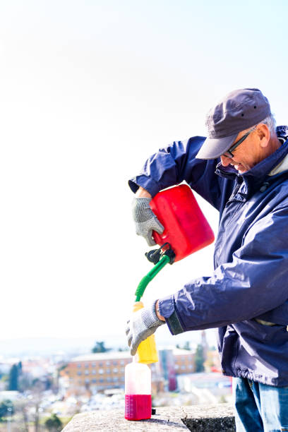 istock Man Pouring Engine Oil into Plastic Gasoline Can Preparing the Perfect Mixture 1441495496