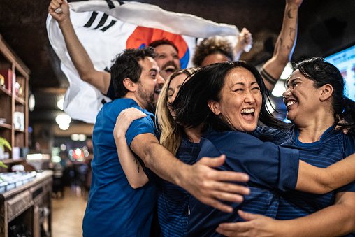 Friends rooting for South Korean team and celebrating at bar