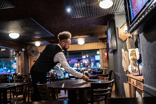 Waiter setting the table at a bar