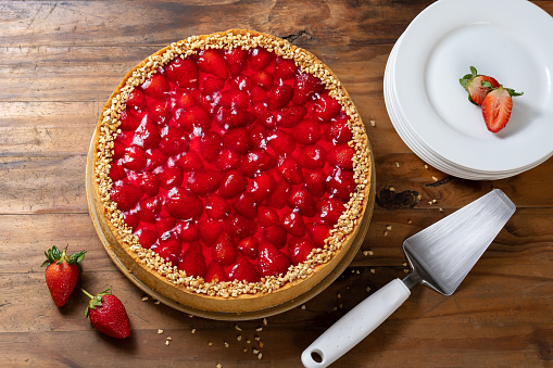 Strawberry pie, white plate on the side, on a rustic wooden background