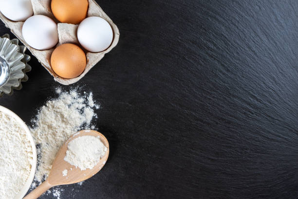 istock Baking ingredients flour, eggs, milk, bakeware on black slate background with copy space 1441501274
