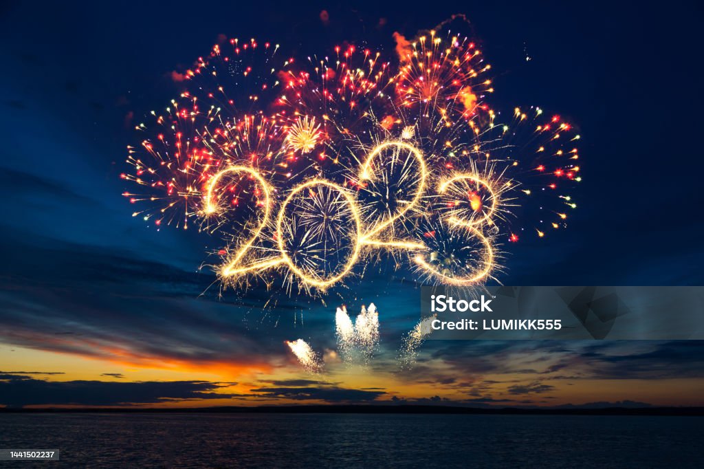 Happy New Year 2023. Happy New Year 2023. Beautiful creative holiday web banner or flyer with red fireworks and Golden sparkling number 2023 on blue sky  over sea 2023 Stock Photo
