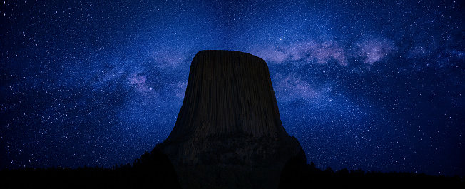 Panoramic photograph of the Milkyway behind the Devils Tower formation in Wyoming.
