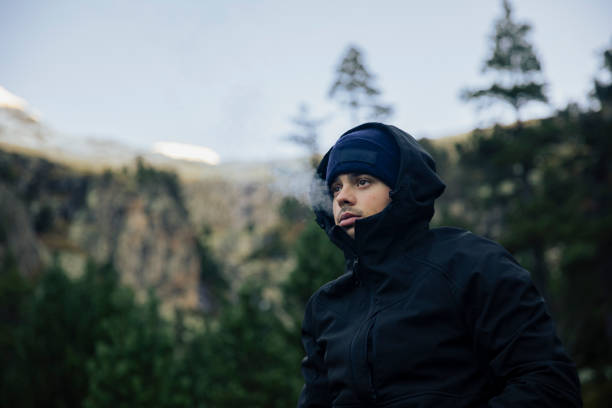 istock Boy with coat and hat smoking a marijuana cigarette in nature 1441504671