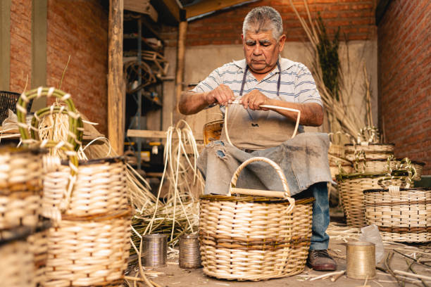 Latin mature artisan making wicker baskets at his workshop stock photo