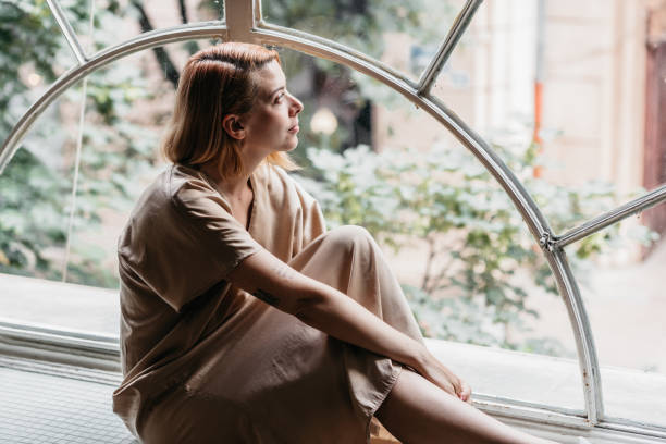 istock Young woman looking through her window 1441508716