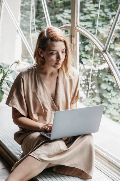 istock Beautiful young redhead typing on her laptop 1441509559
