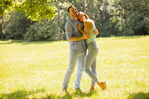 Happy young couple in love at the grass field on a summer day