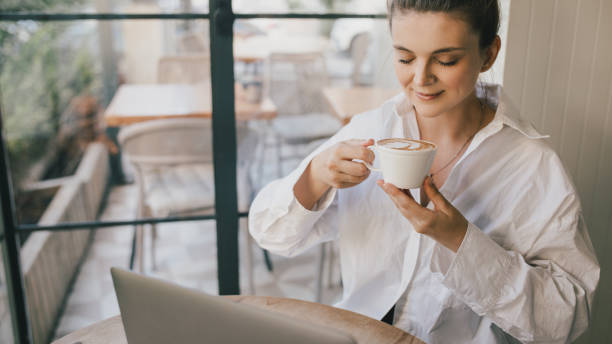 istock Young woman drinking coffee working online using her laptop. 1441516807