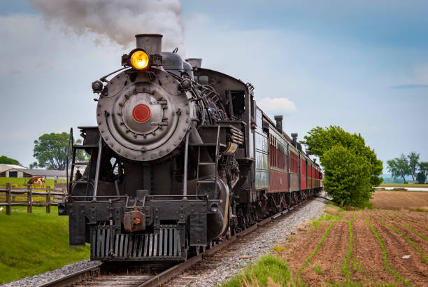 View of a Restored Steam Train Approaching Head-On Blowing Smoke and Steam View of a Restored Steam Train Approaching Head-On Blowing Smoke and Steam on a Spring Day road going steam engine stock pictures, royalty-free photos & images