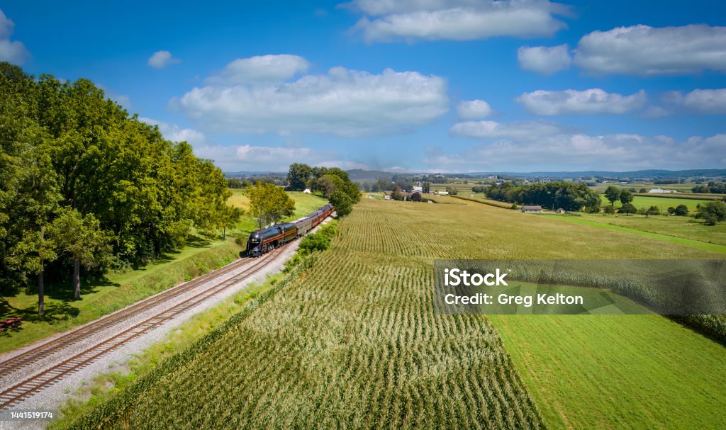Drone View of a Steam Passenger Train Approaching a Track Switch With Green Corn Fields Drone View of a Steam Passenger Train Approaching a Track Switch With Green Corn Fields and Farmlands on a Sunny Summer Day Aerial View Stock Photo