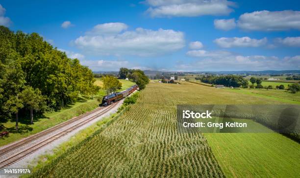 Drone View Of A Steam Passenger Train Approaching A Track Switch With Green Corn Fields Stock Photo - Download Image Now