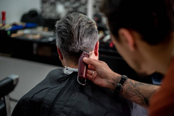 Barber cutting senior woman's hair