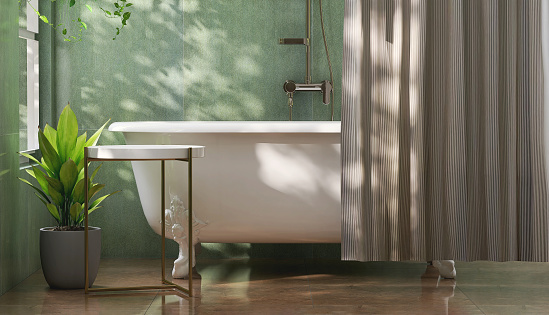 White round side table by ceramic bathtub in modern design bathroom and banana tree with dappled sunlight from window and curtain on green tile wall for personal care and toiletries product display