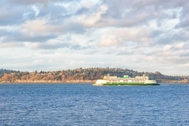 A Washington State Ferry travels across Puget Sound under a dramatic evening sky. The calm waters and moody light create a peaceful maritime scene, capturing the essence of Pacific Northwest transportation and landscape.