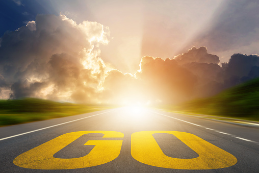 Yellow GO word on asphalt highway road with sunset or sunrise light above asphalt road. Start Your Life. Conceptual image
