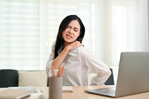 Empresaria asiática que sufre de hombros y dolor de espalda. exceso de trabajo, síndrome de oficina photo