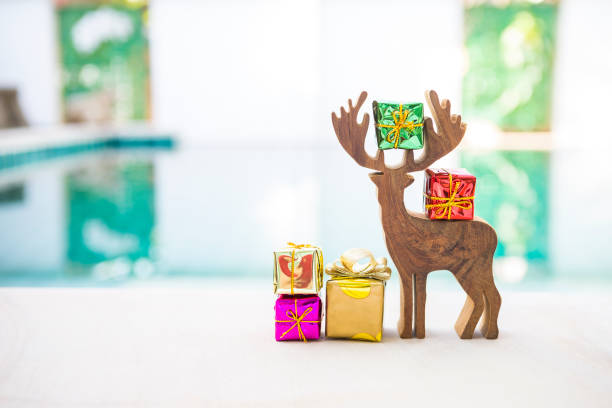 Wooden reindeer with colorful gift box over blurred background, Christmas and New year concept