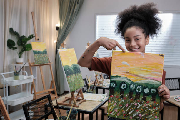 Black girl shows her painting, proud with an acrylic color picture on canvas. stock photo