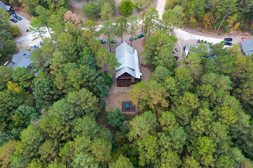 Aerial view of cottages and cars parked nearby in the woods among green trees. Cabins in the forest in Broken Bow, Oklahoma USA.